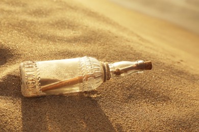 Photo of SOS message in glass bottle on sand