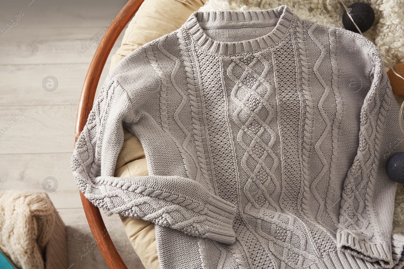 Photo of Warm knitted sweater on armchair in cozy living room, above view