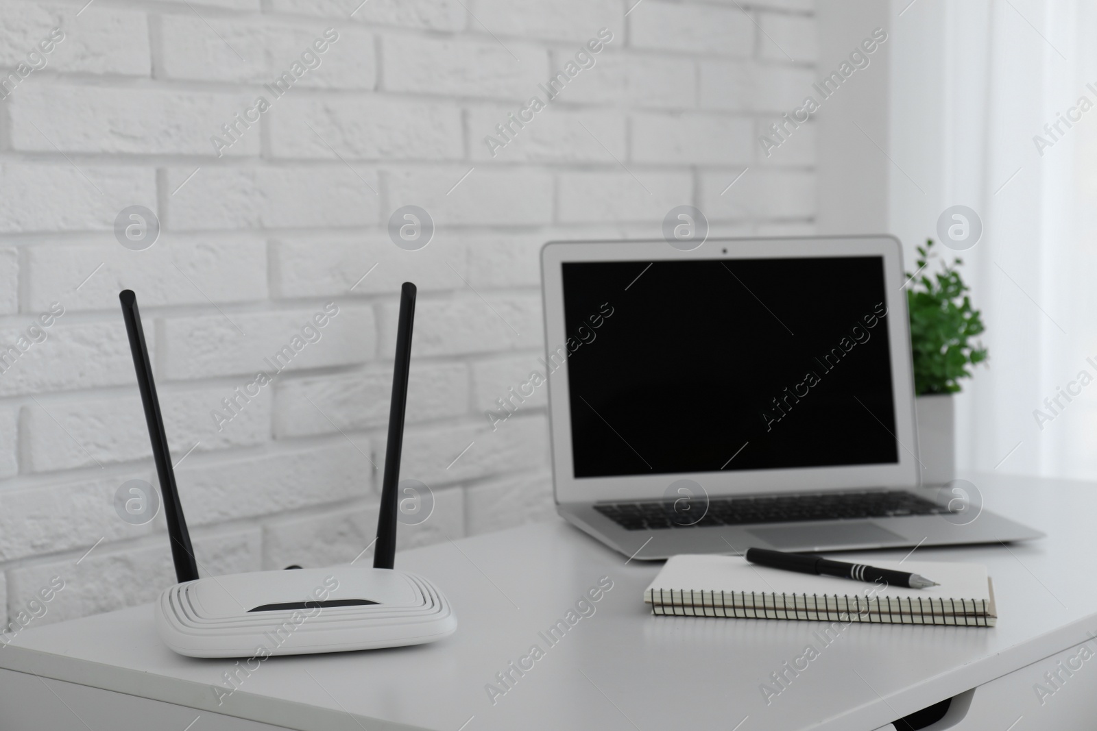 Photo of Router, modern laptop and notebook on white table indoors