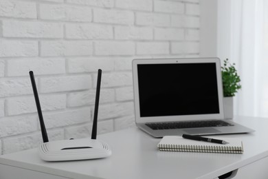 Photo of Router, modern laptop and notebook on white table indoors