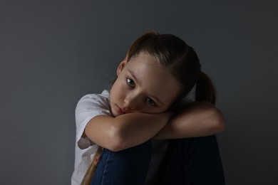 Photo of Sad girl sitting near dark grey background