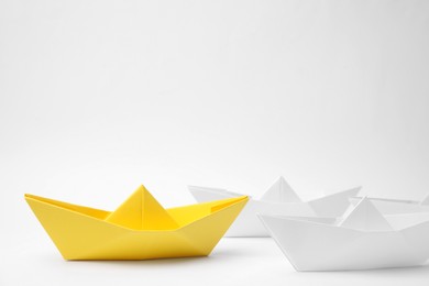 Group of paper boats following yellow one on white background. Leadership concept