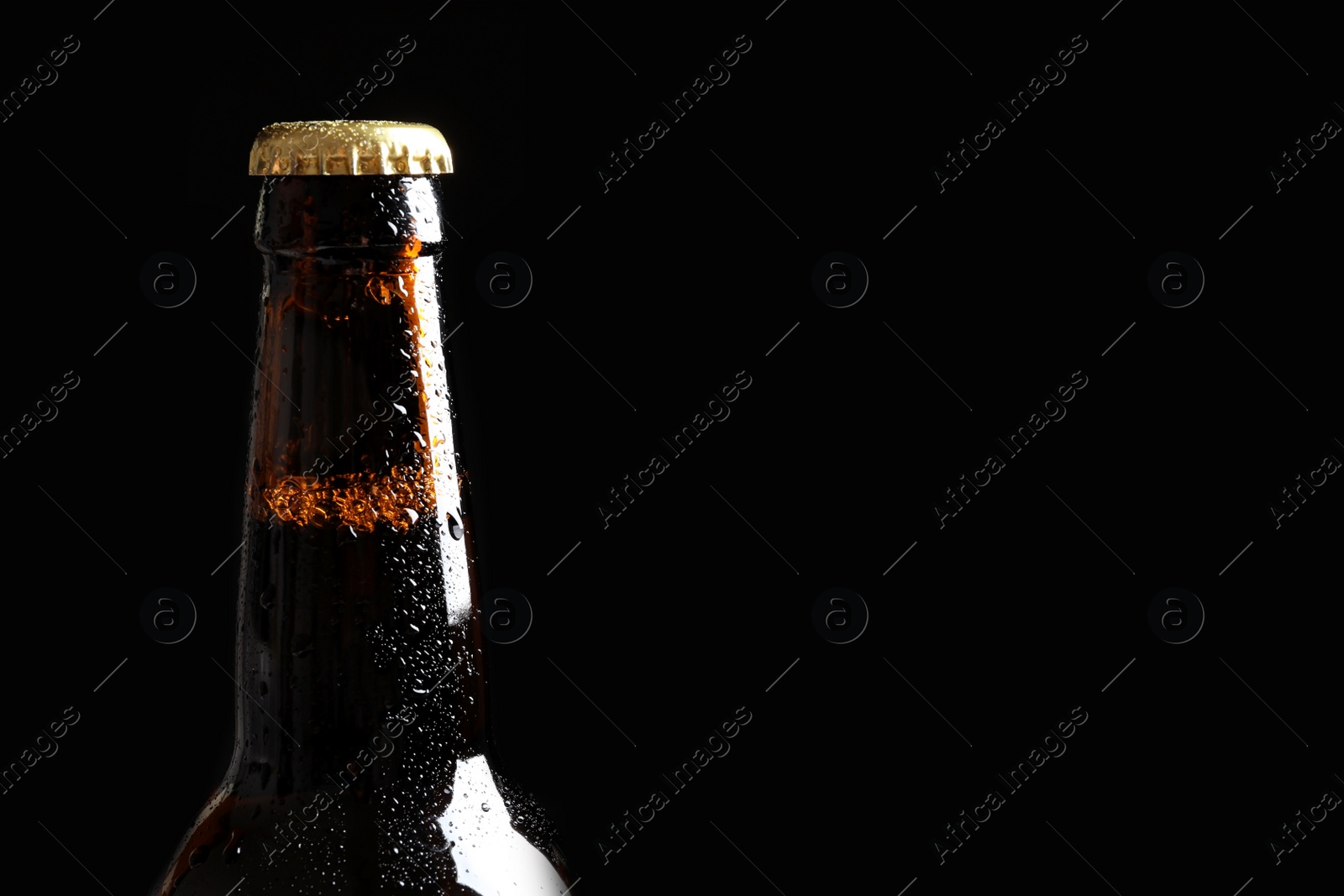 Photo of Bottle of tasty cold beer on black background, closeup