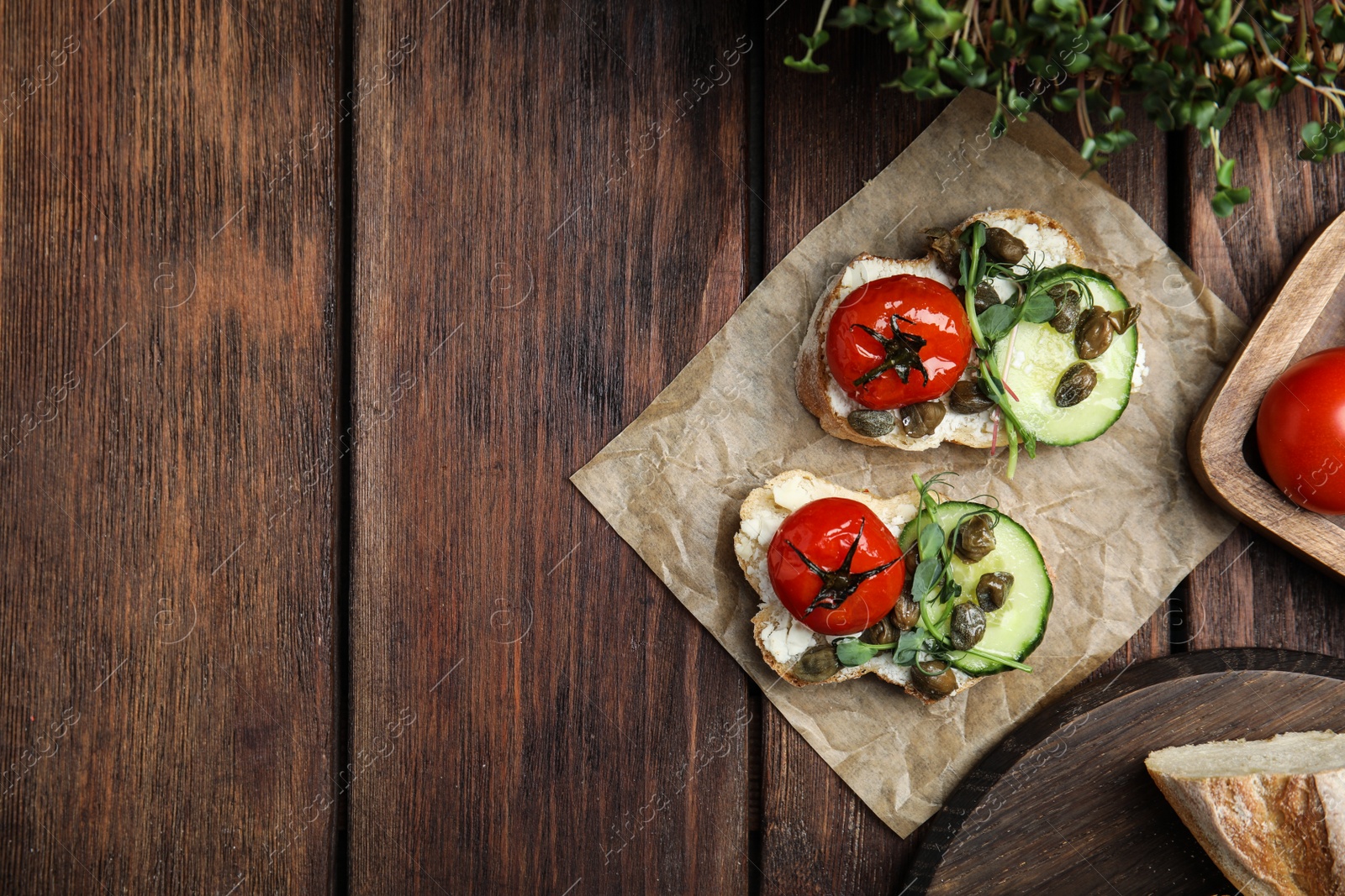 Photo of Tasty bruschettas with vegetables and capers served on wooden table, flat lay. Space for text