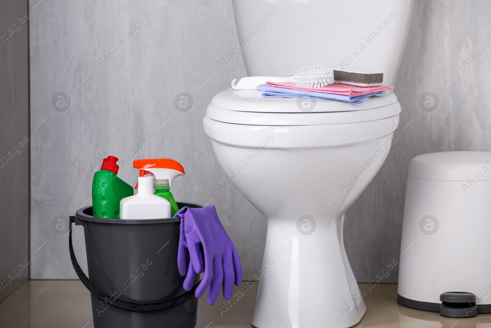 Photo of Bucket with toilet cleaning supplies on floor indoors