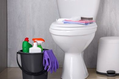 Bucket with toilet cleaning supplies on floor indoors