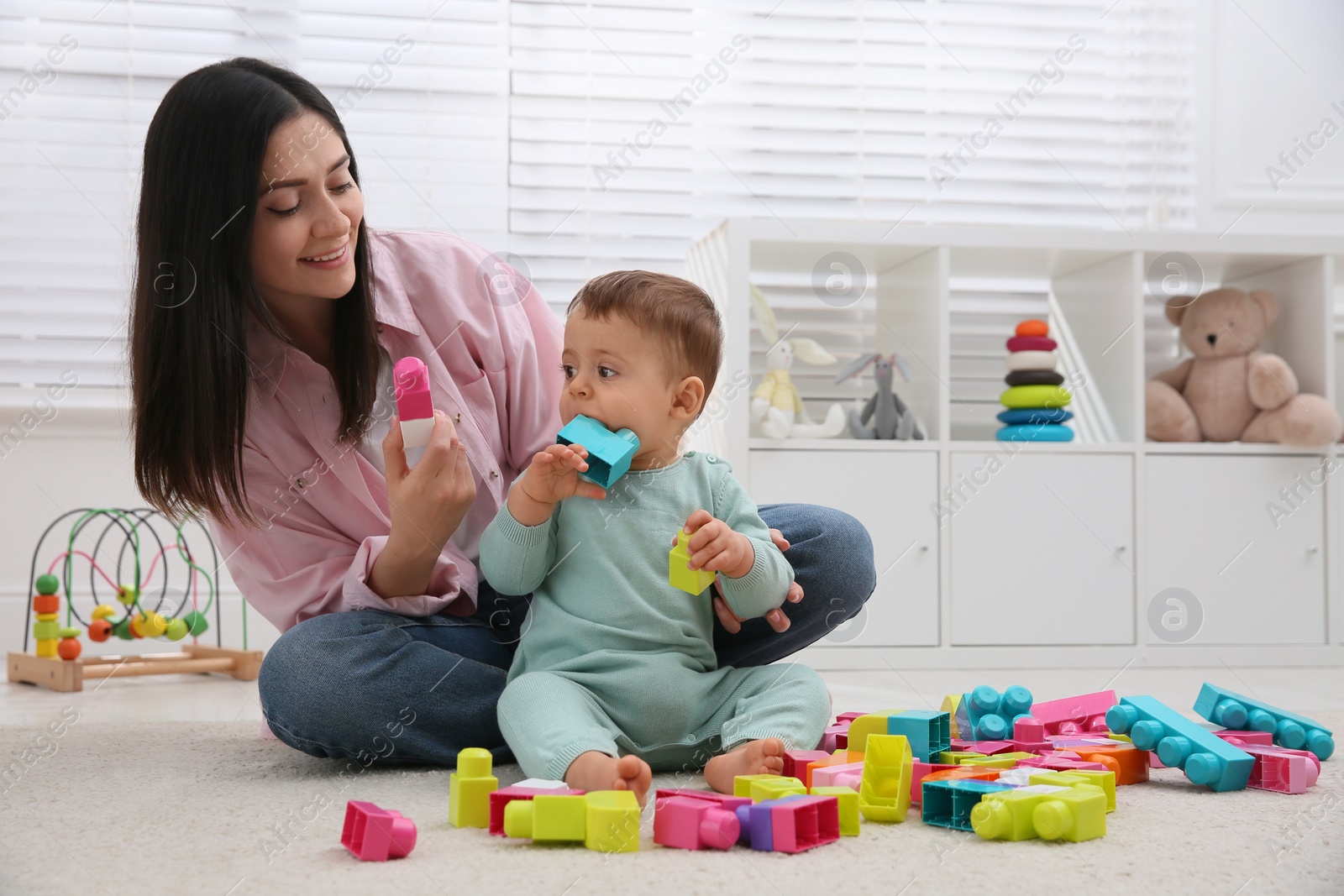 Photo of Cute baby boy playing with mother and building blocks on floor at home