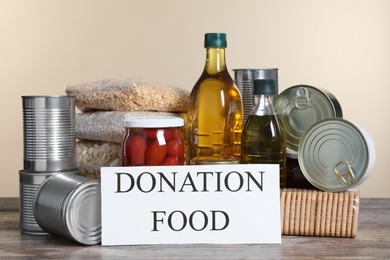 Photo of Card with words Donation Food and different products on wooden table