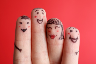 Photo of Four fingers with drawings of happy faces on red background