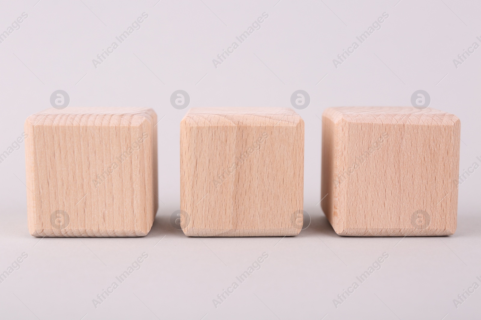 Photo of Blank wooden cubes on light grey background, closeup