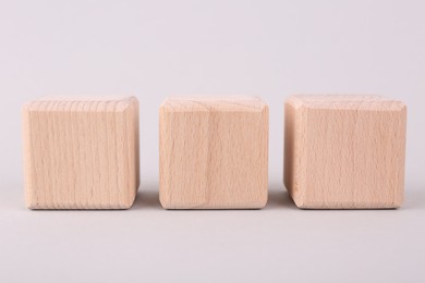 Blank wooden cubes on light grey background, closeup