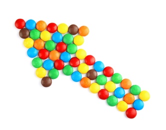 Arrow made of colorful candies on white background, top view