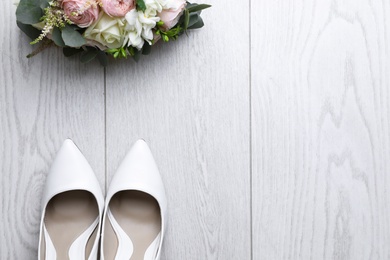 Photo of Pair of wedding high heel shoes and beautiful bouquet on white wooden floor, flat lay. Space for text