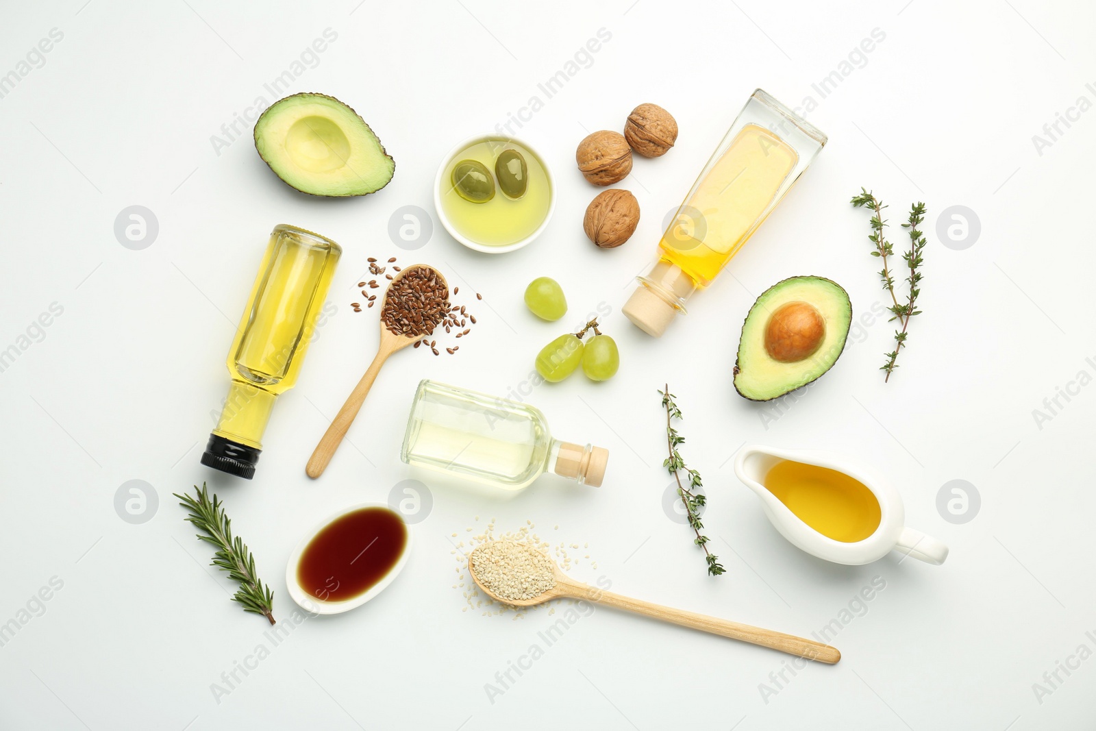 Photo of Vegetable fats. Different oils in glass bottles and ingredients on white table, flat lay