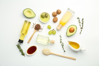 Photo of Vegetable fats. Different oils in glass bottles and ingredients on white table, flat lay