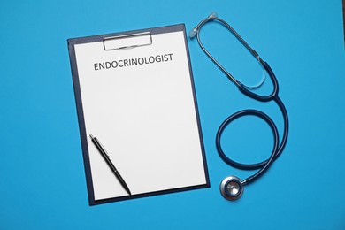 Image of Endocrinologist. Clipboard, stethoscope and pen on light blue background, top view