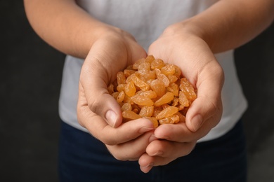 Photo of Woman holding raisins on black background, closeup