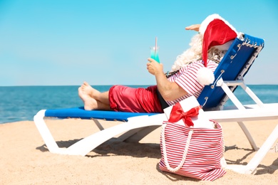 Authentic Santa Claus with cocktail resting on lounge chair at resort