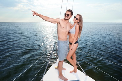 Photo of Young man and his beautiful girlfriend in bikini on yacht. Happy couple on vacation