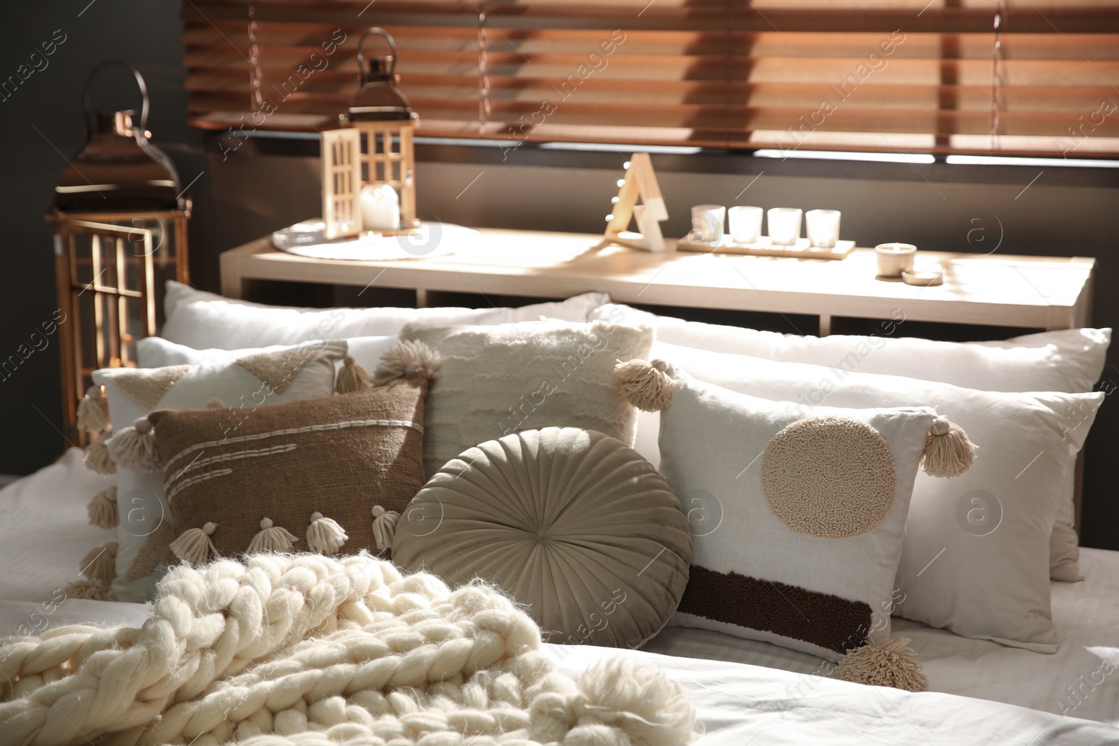 Photo of Cozy bedroom interior with knitted blanket and cushions