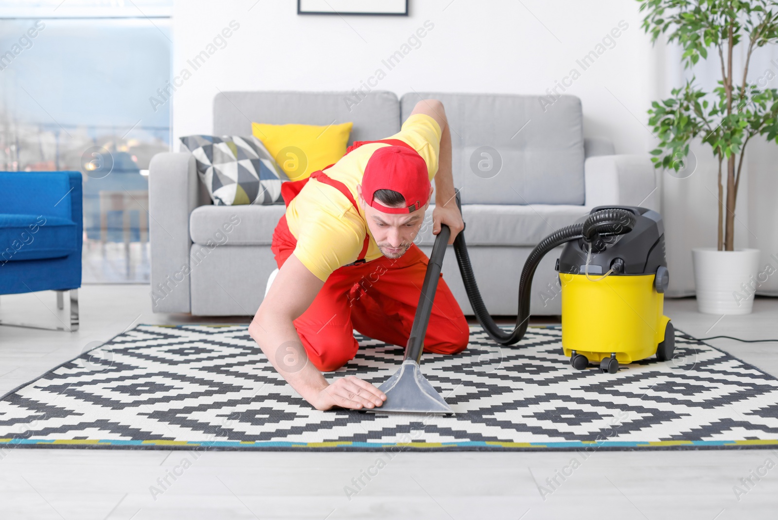 Photo of Mature man hoovering carpet with vacuum cleaner in living room