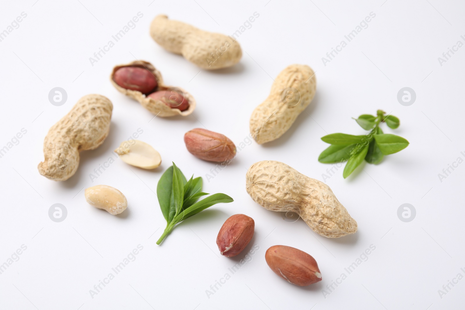 Photo of Fresh peanuts and leaves on white table, closeup