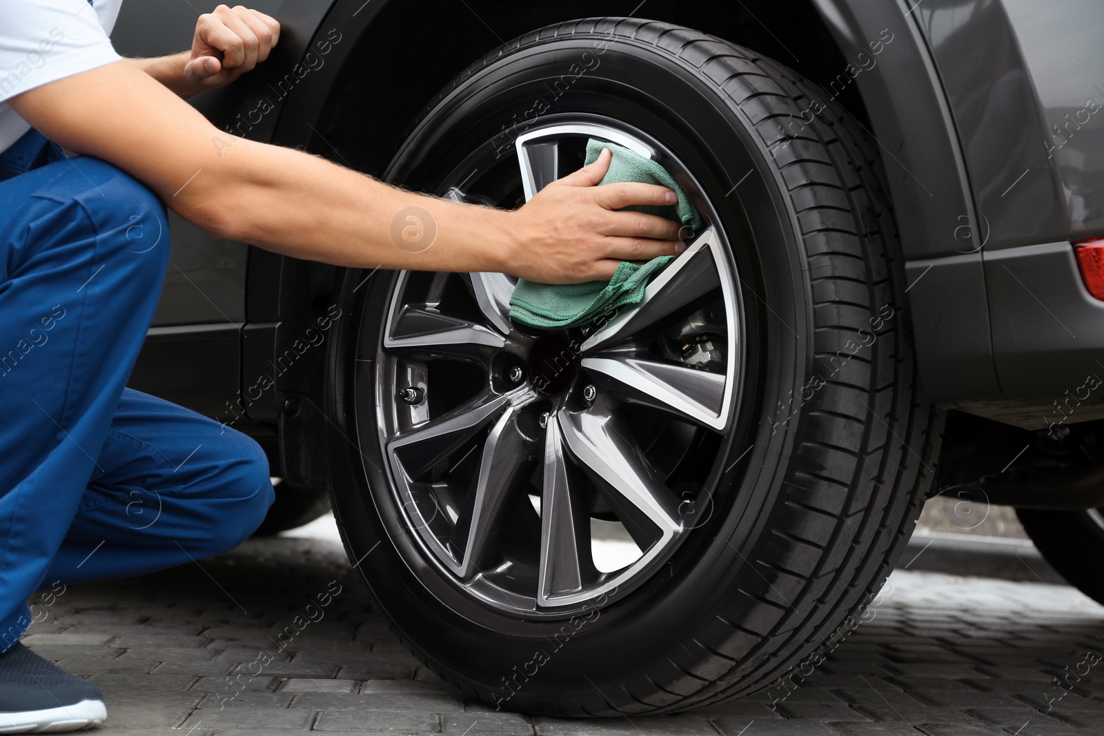 Photo of Man washing car wheel with rag, closeup