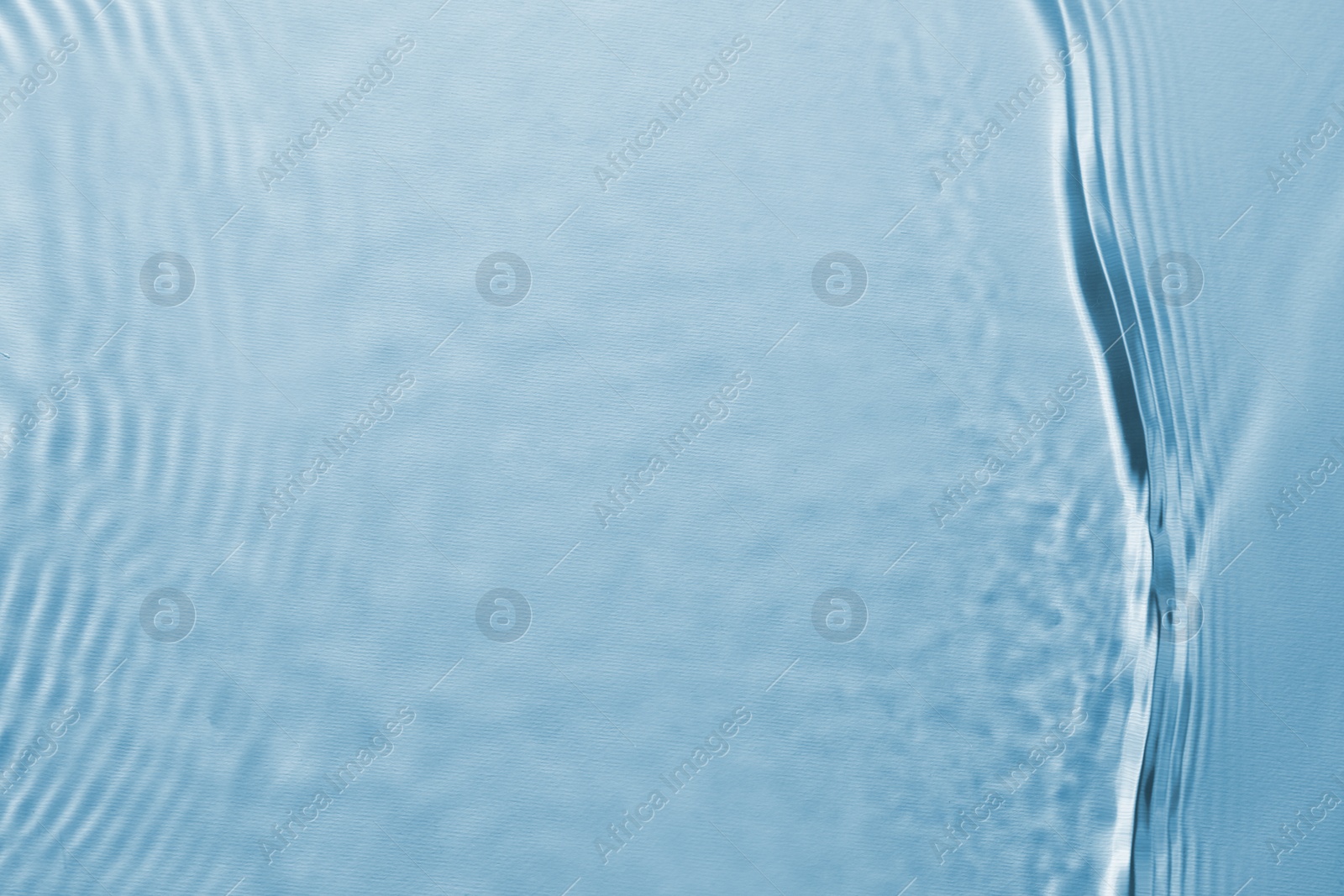 Image of Rippled surface of clear water on light blue background, top view