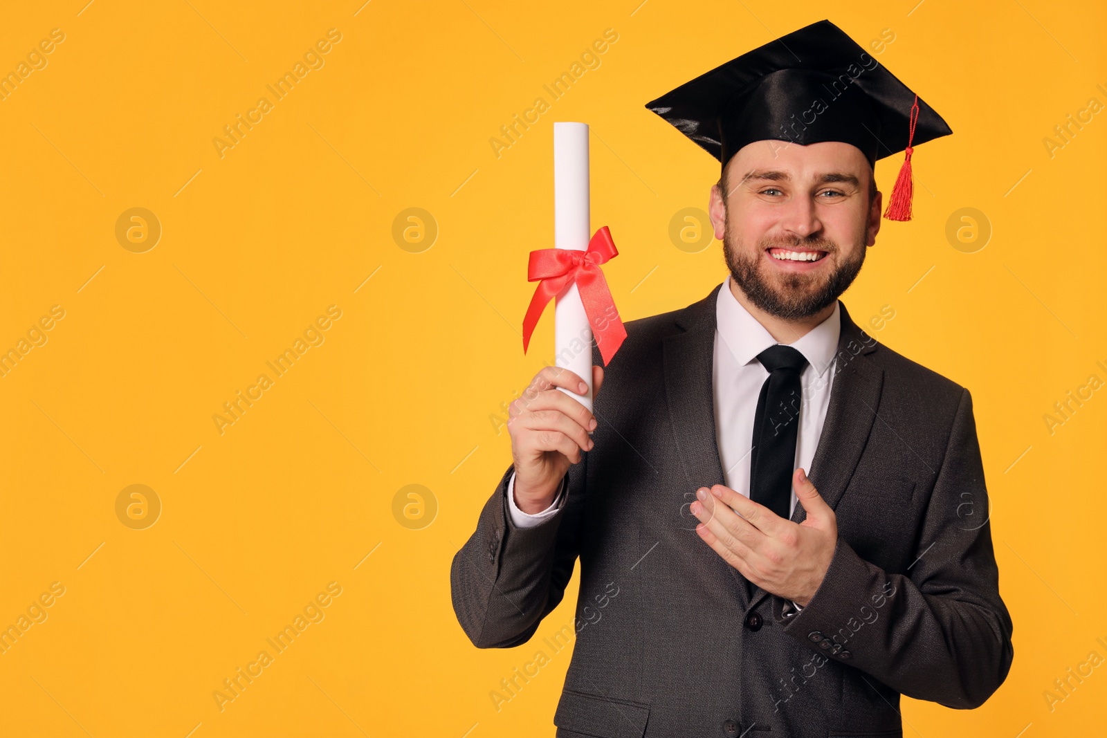 Photo of Happy student with graduation hat and diploma on yellow background. Space for text