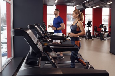 Beautiful couple training on treadmills in gym