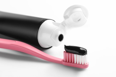 Photo of Brush with charcoal toothpaste on white background