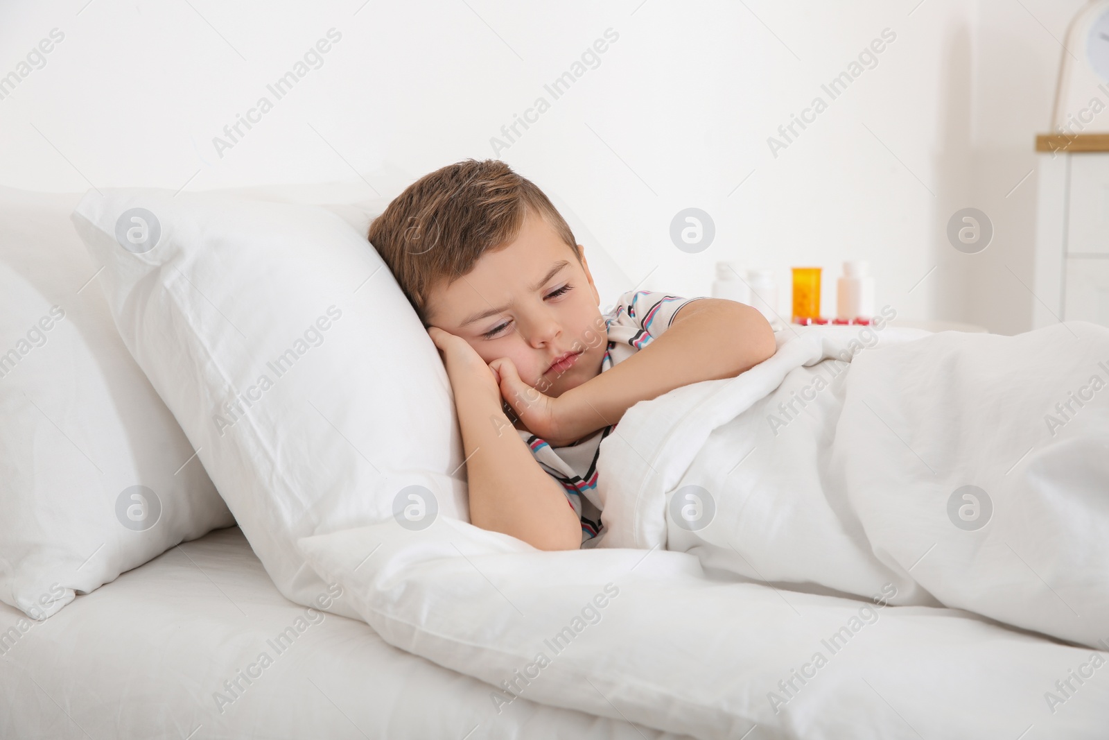Photo of Sick boy lying in bed. Little patient waiting for doctor at home