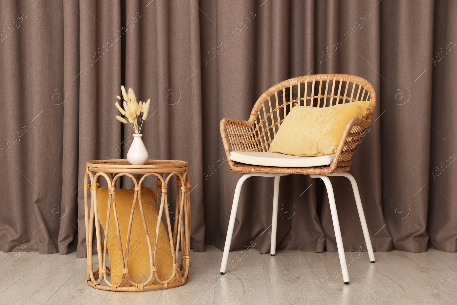 Photo of Armchair and wicker table with vase near elegant curtains indoors