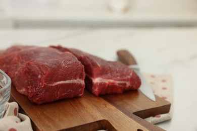 Photo of Board with beef meat on white table, closeup