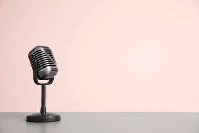Vintage microphone on light grey table, space for text