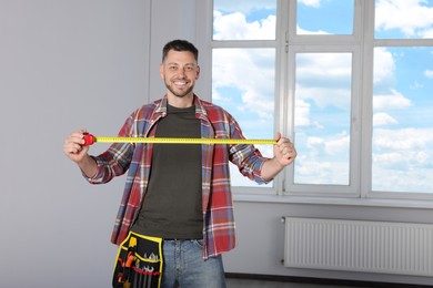Handsome worker with measuring tape in empty room