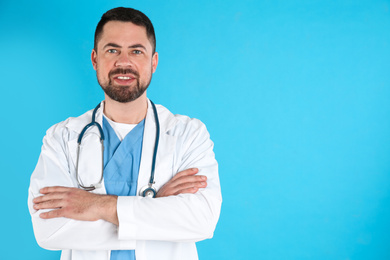 Photo of Mature doctor with stethoscope on blue background, space for text