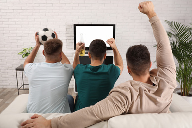 Group of friends watching football at home