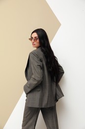 Photo of Beautiful woman with sunglasses in formal suit on color background. Business attire