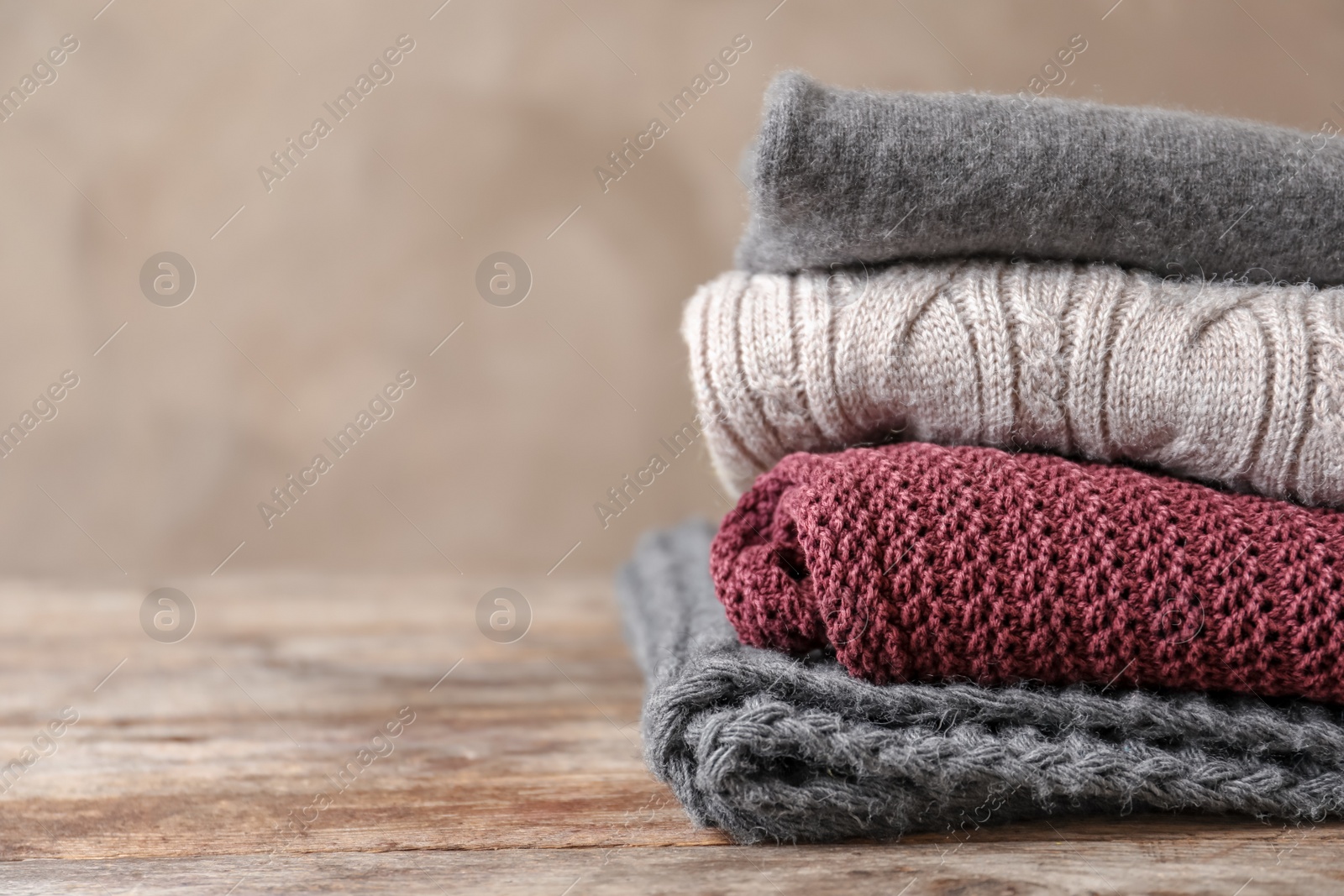 Photo of Stack of warm knitted clothes on table