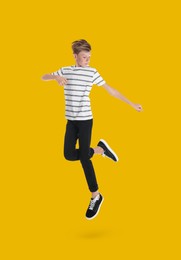 Teenage boy jumping on golden background, full length portrait