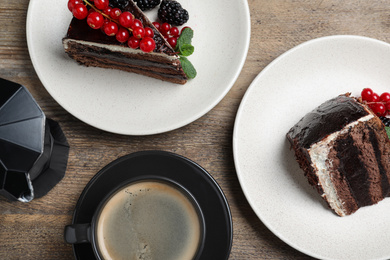 Photo of Tasty chocolate cake with berries on wooden table, flat lay