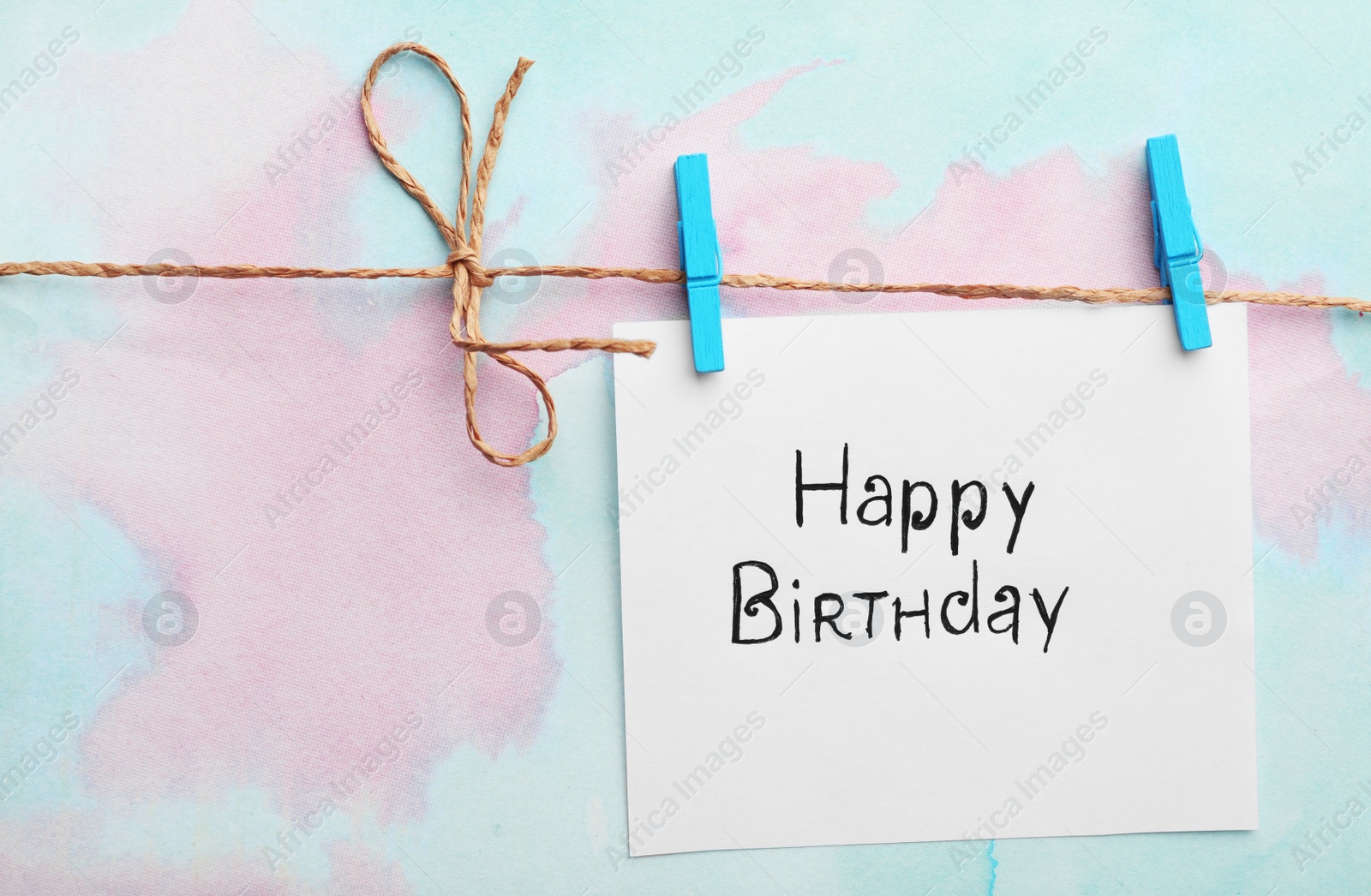 Photo of Card with words HAPPY BIRTHDAY hanging on clothesline, color background