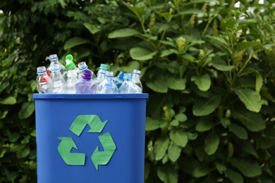 Many used bottles in trash bin outdoors, space for text. Plastic recycling