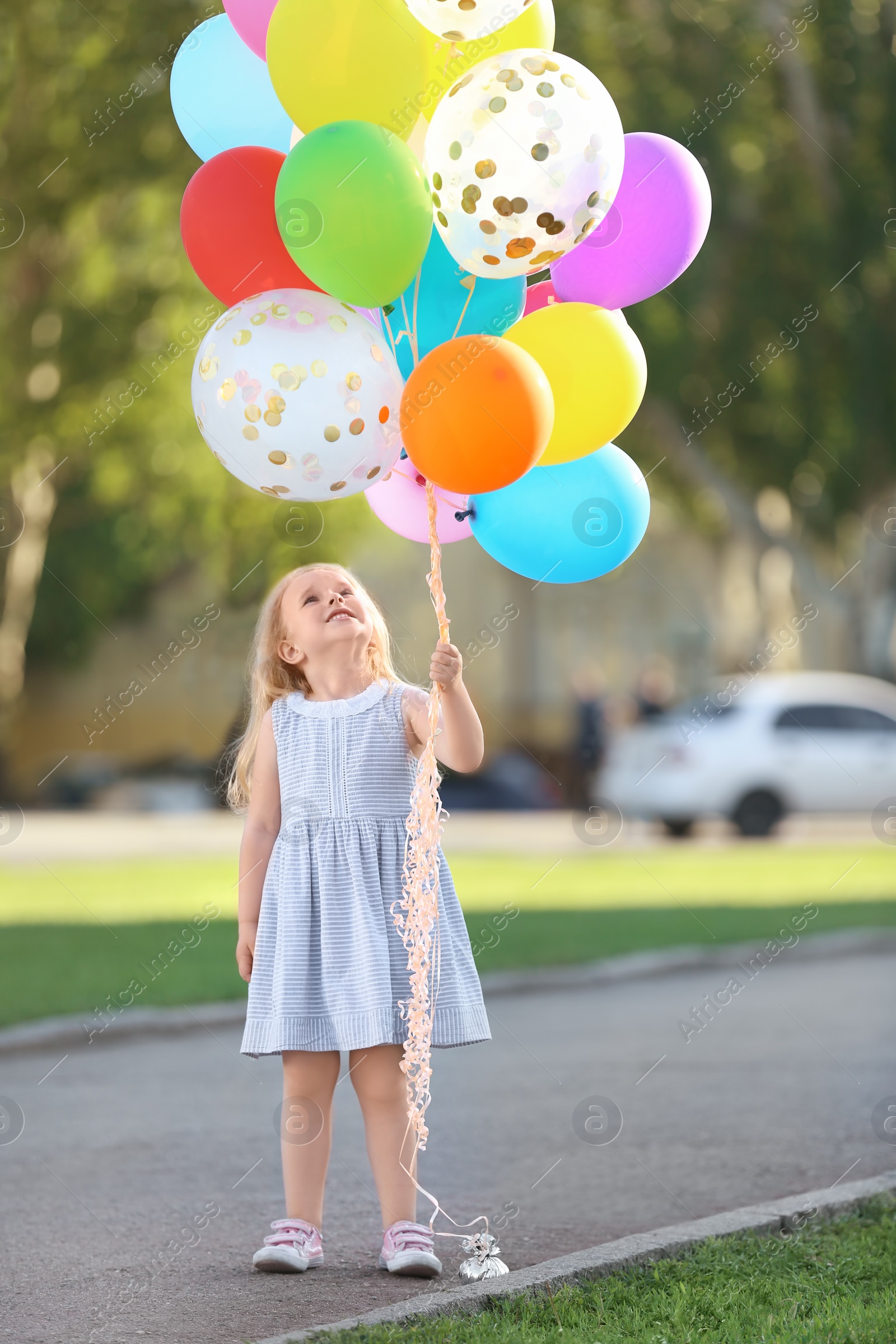 Photo of Cute girl with colorful balloons in park on sunny day