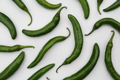 Many green hot chili peppers on white background, flat lay