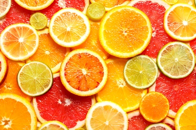 Slices of fresh citrus fruits as background, top view