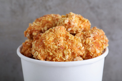 Photo of Bucket with yummy nuggets on blurred grey background, closeup