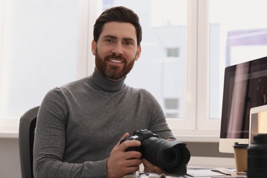 Photo of Professional photographer with digital camera at table indoors