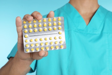 Photo of Male doctor holding pills on color background, closeup. Medical object